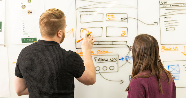 two students wireframing on a white board