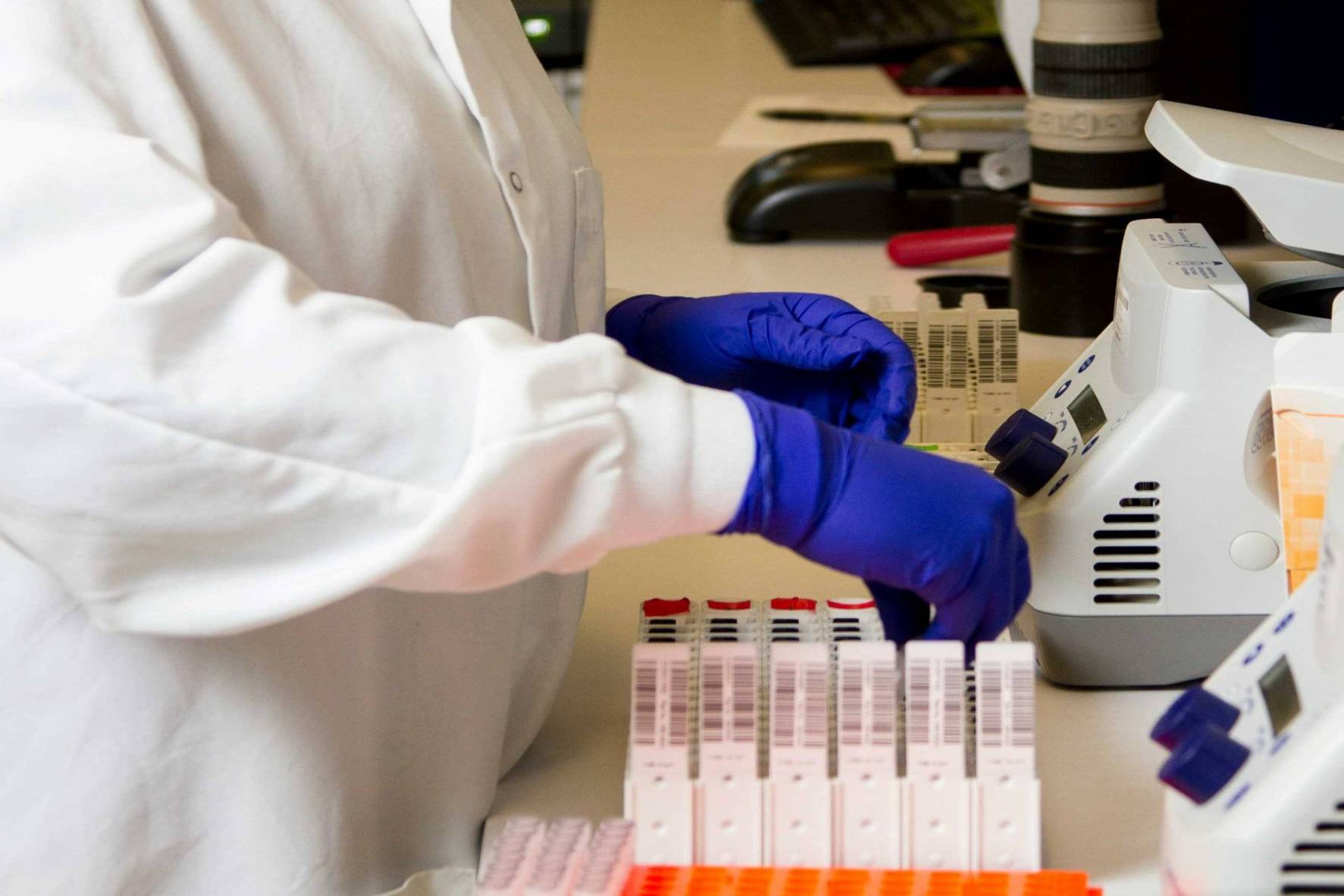 Photo by National Cancer Institute Unsplash Image shows someone in protective clothing organizing medical vials 