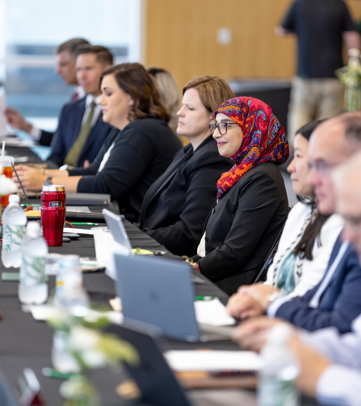 Group of people sitting around a conference table, with CIDO Rasha Qudisat in focus.