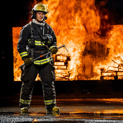 Firefighter holding an ax infront of a fire