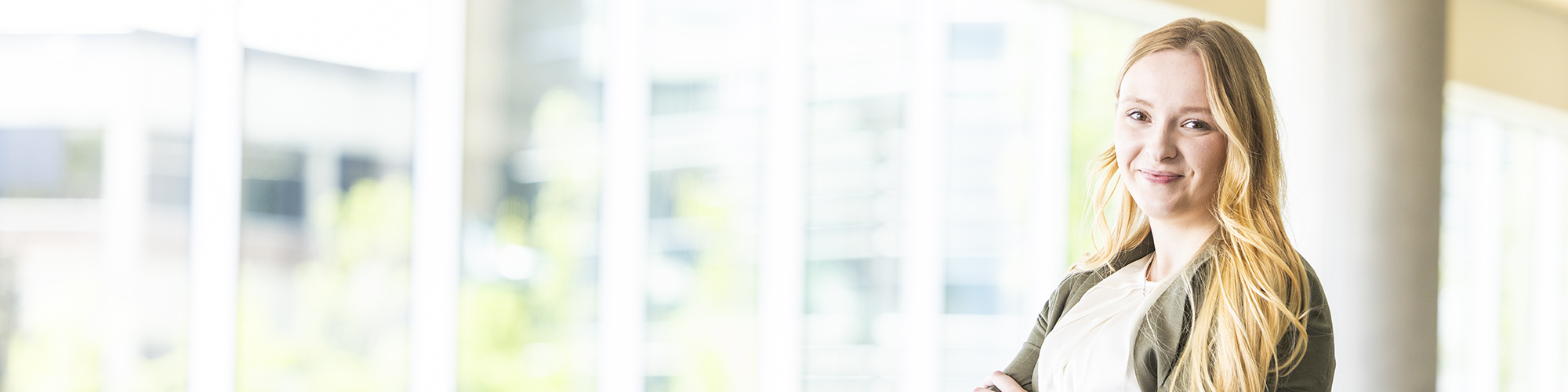 UVU First-Gen Student looking out a large window at the main campus.