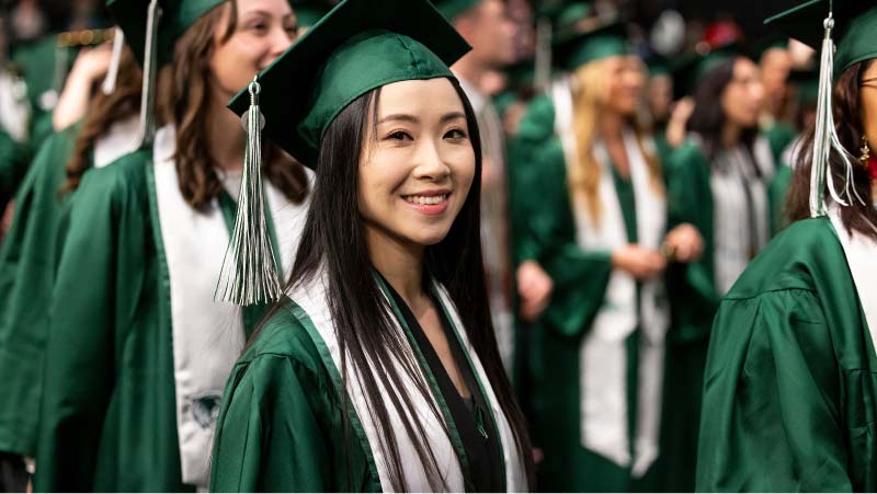 UVU graduates standing in the UCCU center for graduation.