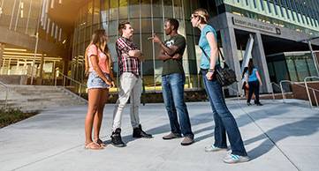 Four students standing outside the SLWC, talking