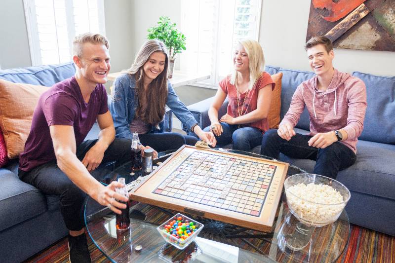 group of four students people hanging out, playing a board game