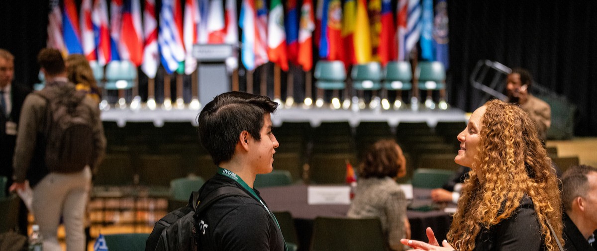 Students having a conversation, multiple country flags are placed behind them