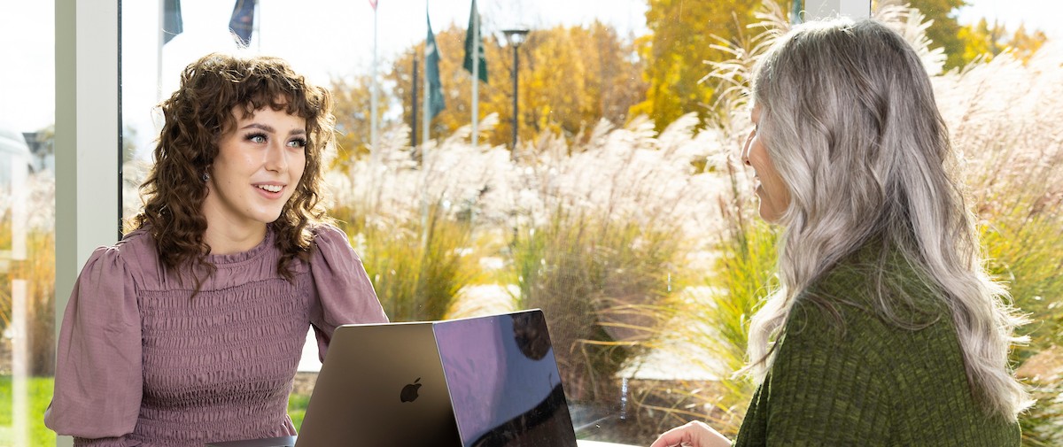 students facing each other with laptops in front of them