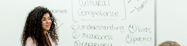 UVU Cultural Competency Workshop presenter standing in front of white board with cultural competency terms listed