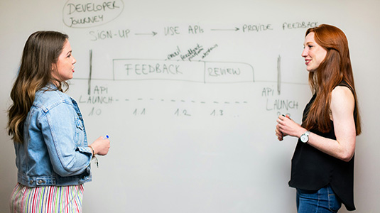 two women standing at a whiteboard