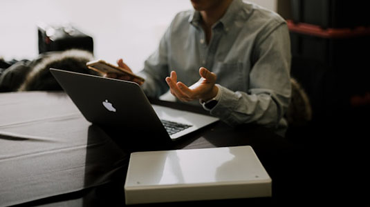 man seated at desk with macbook