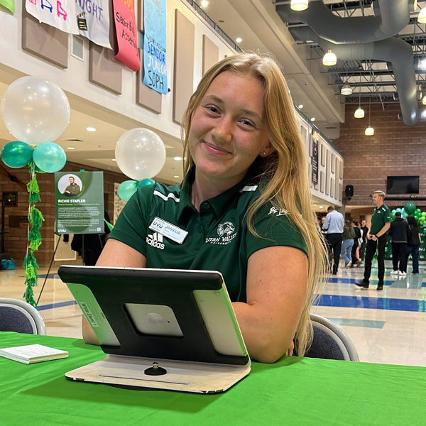 A UVU ambassador happily checking people in to an event