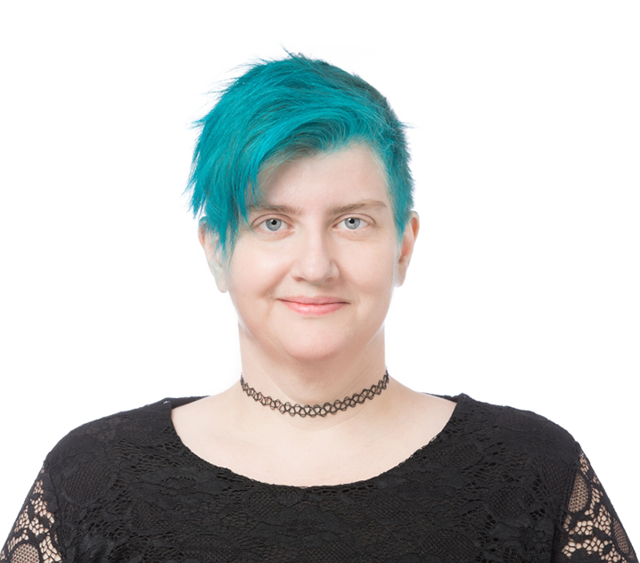 a woman with turquoise hair and wearing a black top smiling at the camera