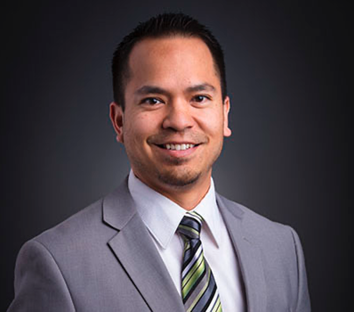 a man wearing a suit and tie smiling at the camera