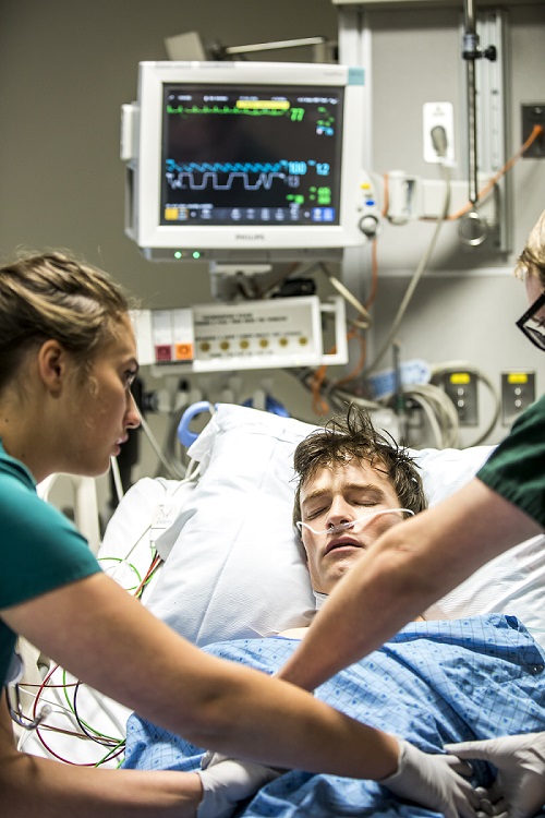 Man in medical bed being looked over by two doctors
