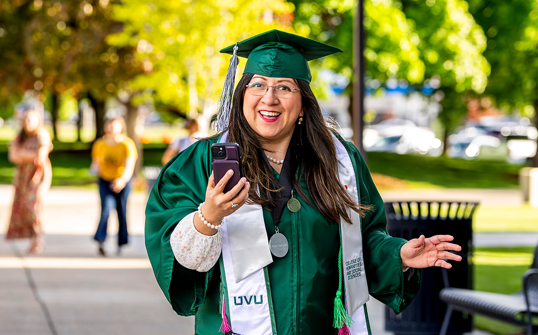 A UVU grad smiling walking outside.