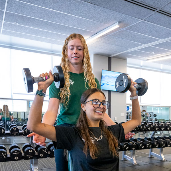 UVU personal trainer working with student on free weights