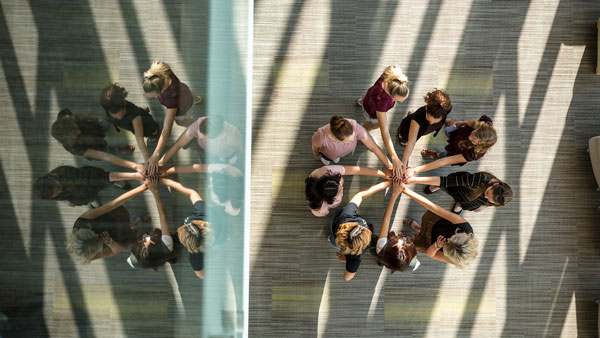 group of students with hands clasped in the middle of a circle