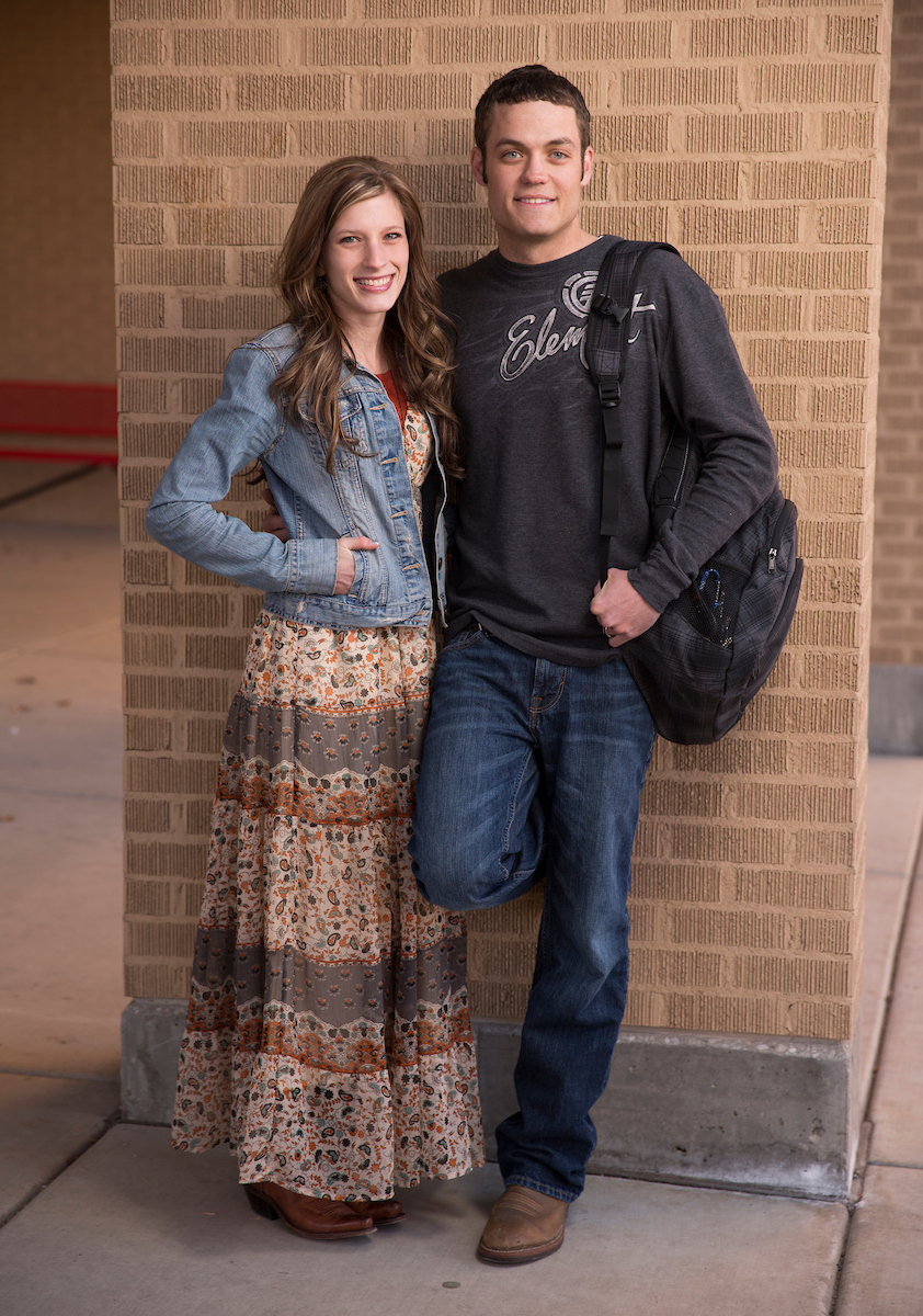 Hetero couple standing side-by-side against a brick background Hetero couple standing side-by-side against a brick background
