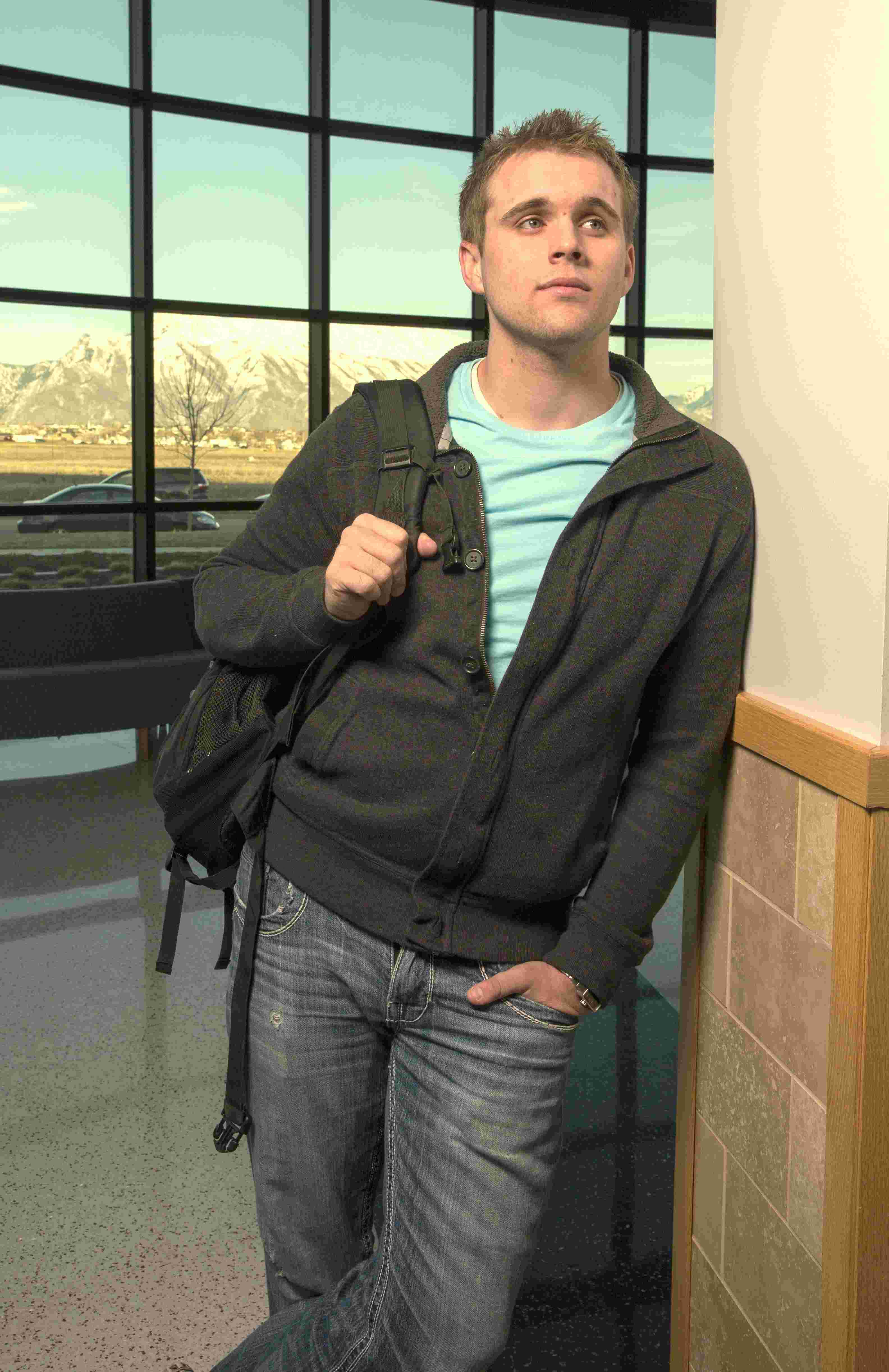 male student leaning against a wall