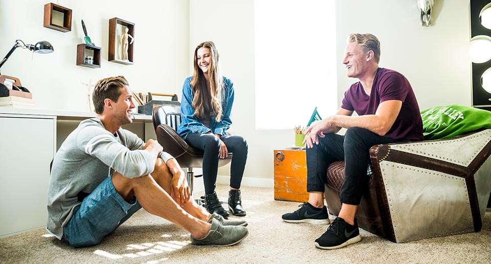 Three students gather in an apartment.