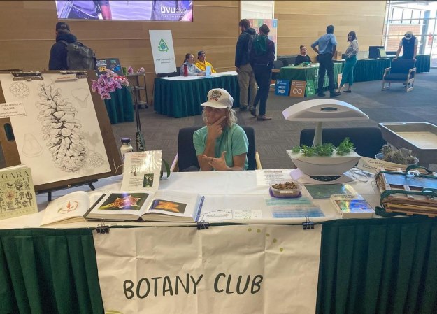 Person sitting at a table with a sign that says Botany Club