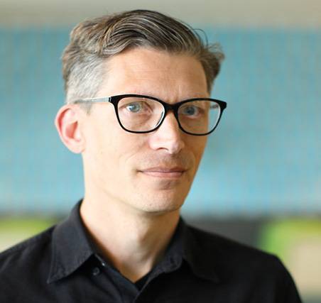 Photo of Jared Stein  a caucasian male with greying hair wearing a black collared shirt and glasses