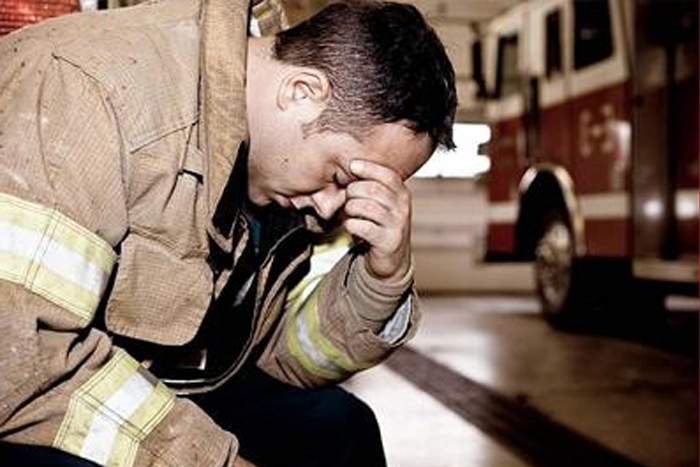 Firefighter after a fire in the firehouse sitting with his head on his hand
