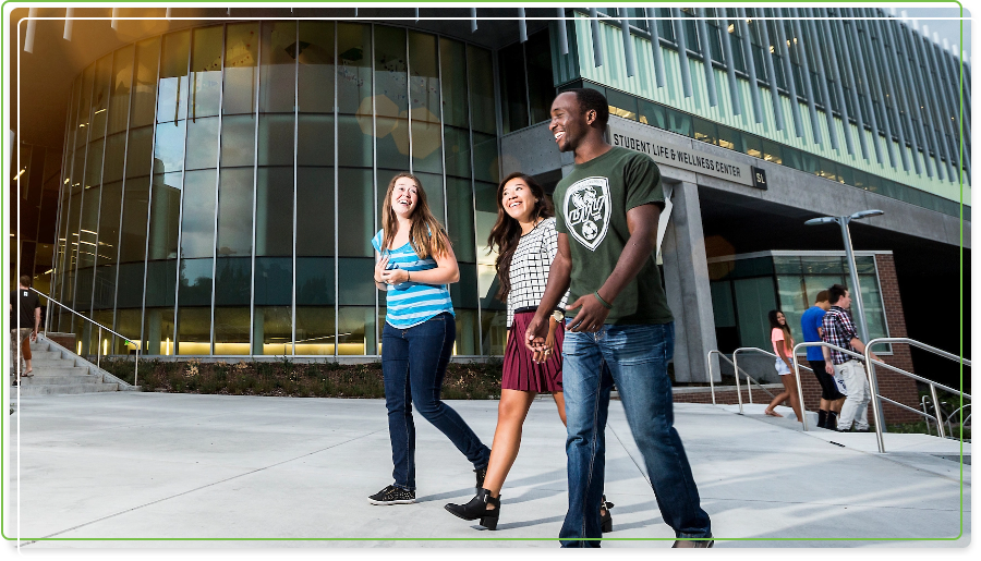 A group of 3 diverse students walking on campus laughing together