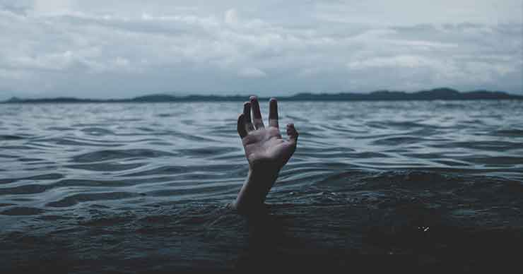 A hand sticking up out of a body of water, as if the person is drowning.