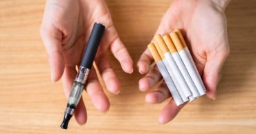 Picture of hands holding electronic cigarette and cigarettes.