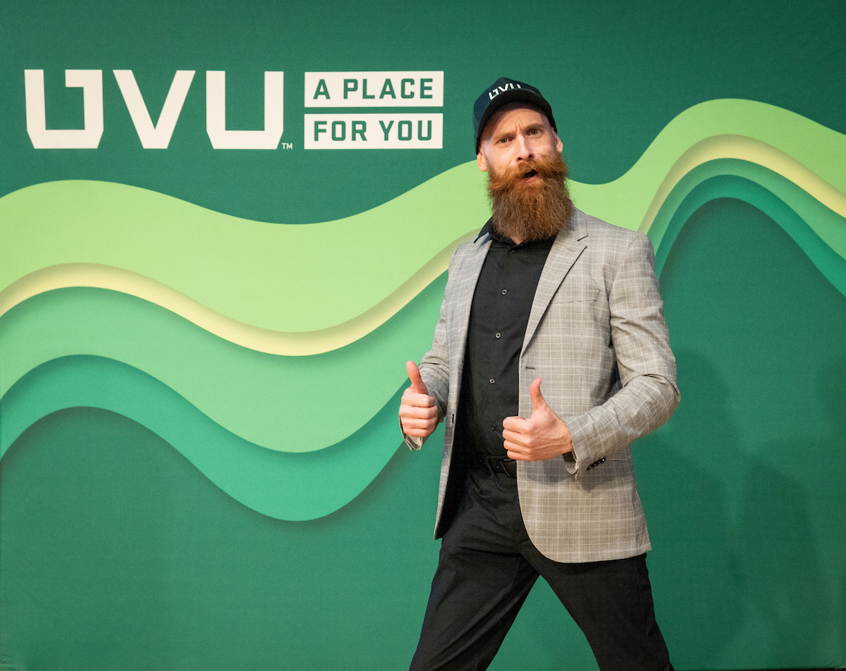 Man excited in front of green backdrop with UVU logo